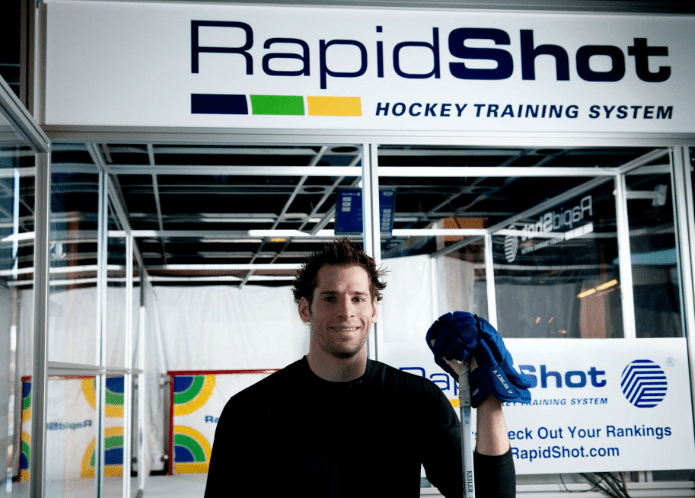 Hockey Player posing in front of a RapidShot training system